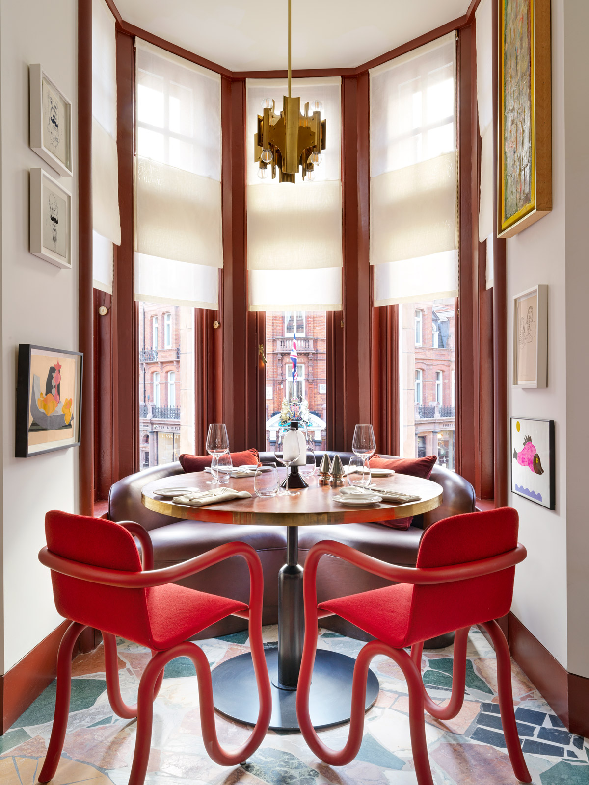 A dining table with red chairs and round sofa