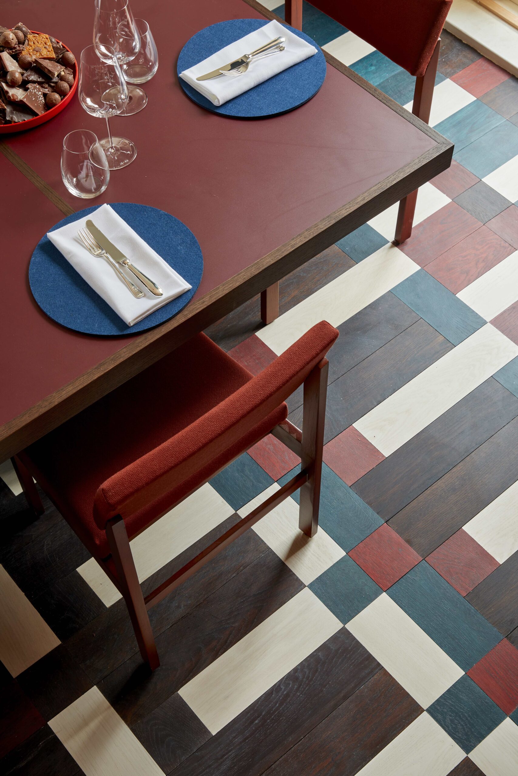 A burgundy set of tables and chairs on a multi patterned floor