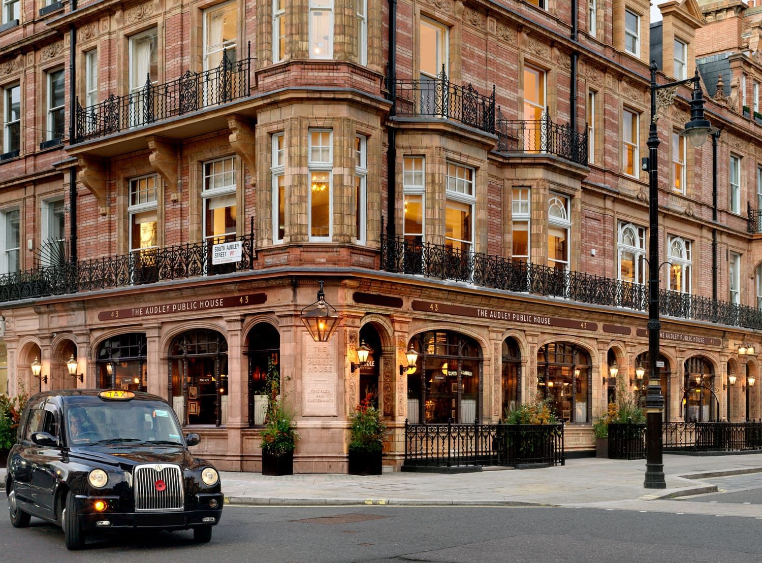 An outside view of The Audley Public House with a taxi driving across the road