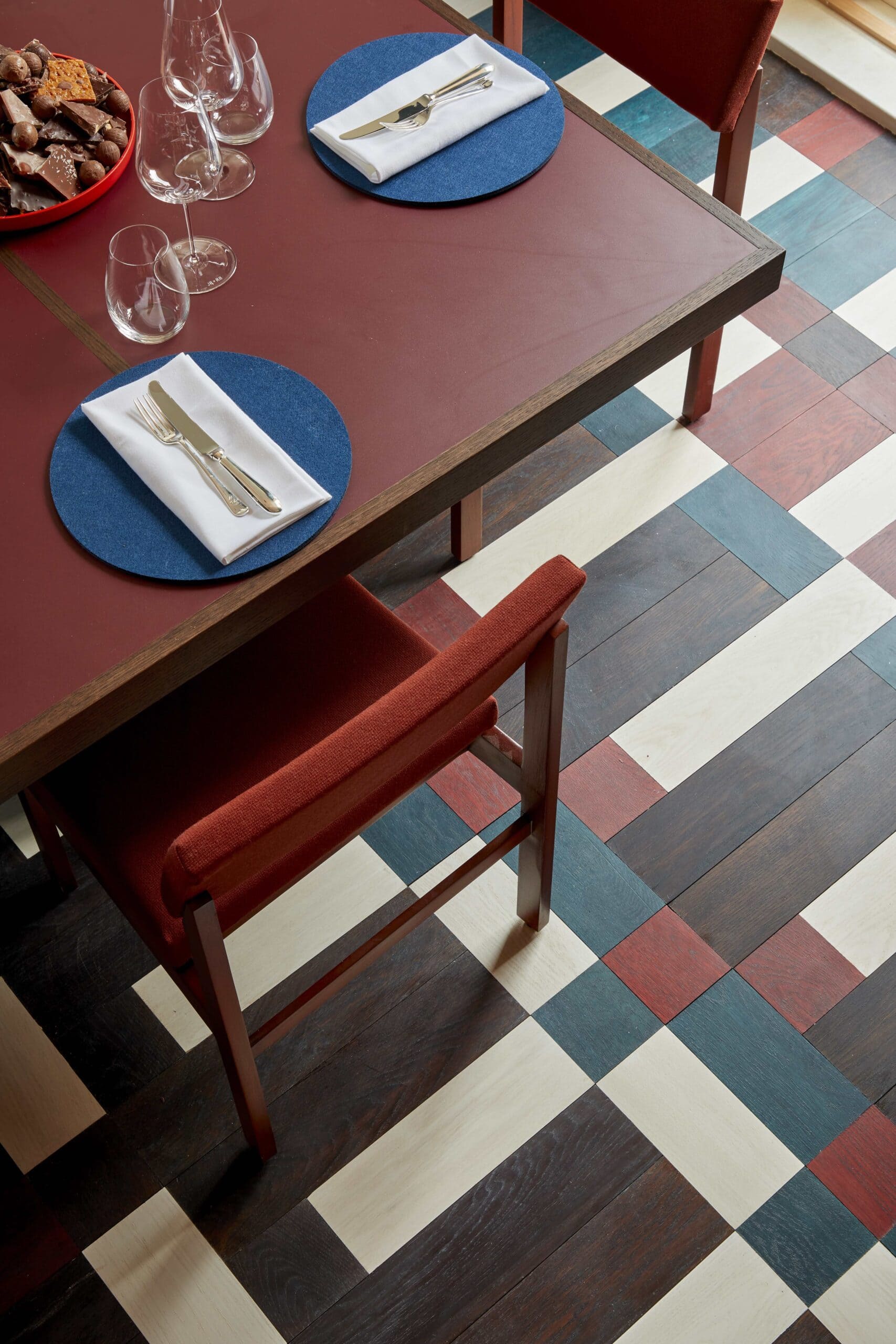 A burgundy set of tables and chairs on a flooring installed by artisan Ian Harper