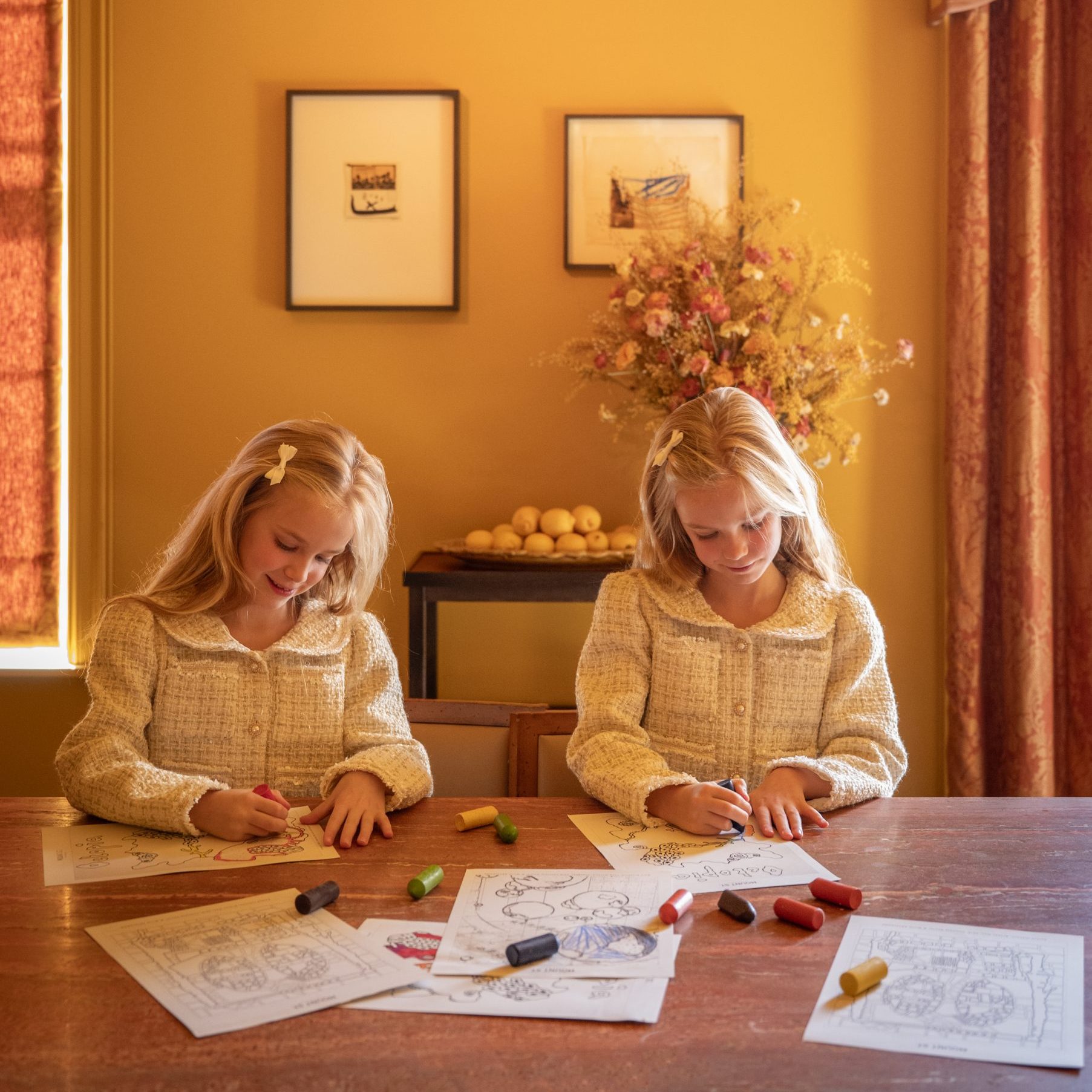 Two blonde girls in the Italian Dining Room, colouring in with crayons