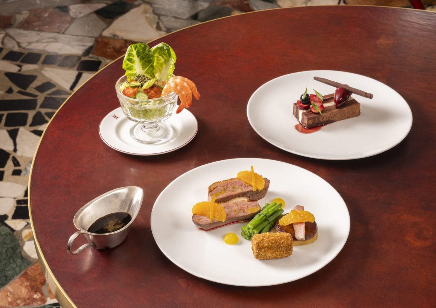 Retro Menu – three dishes on a red leather table: Prawn cocktail, Duck à l'orange, and Black forest gâteau