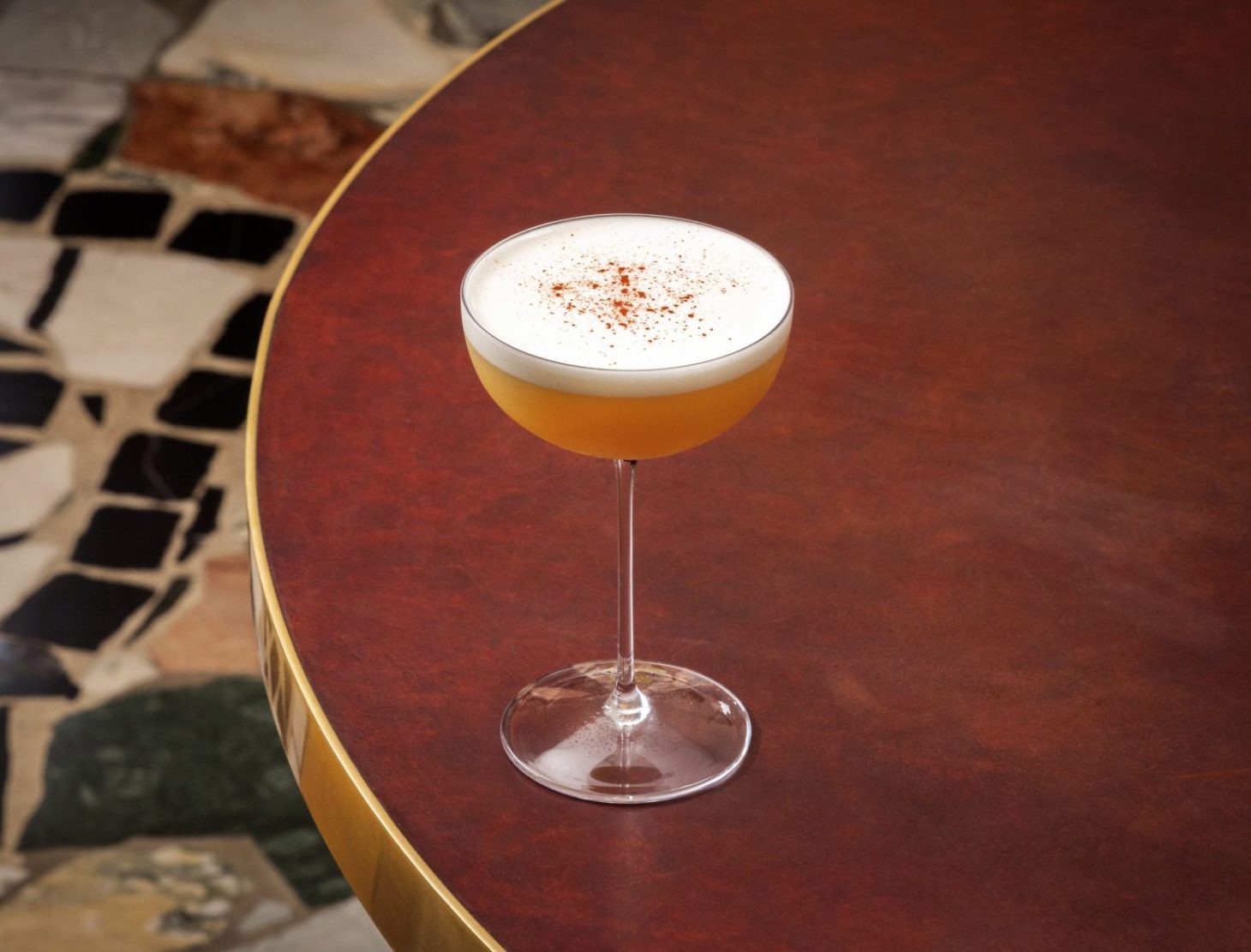 A cocktail on a red, leather top table